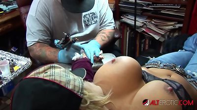 Shyla Stylez receives a tattoo while fondling her breasts